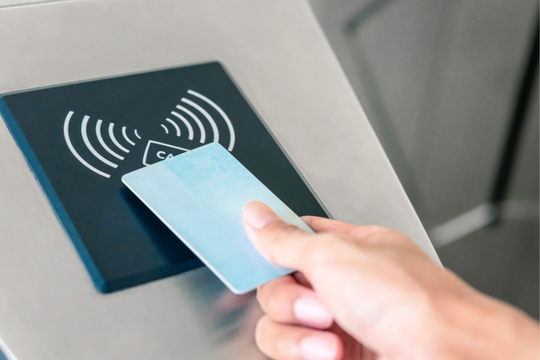 Hand holding an access card to a card reader.