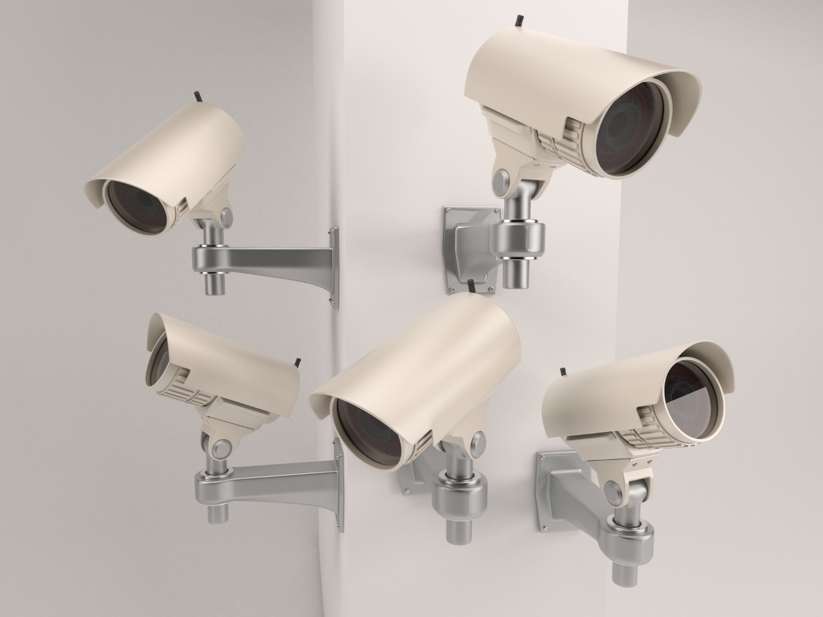 Multiple beige bullet-style CCTV cameras mounted on a wall, demonstrating common business surveillance cameras.