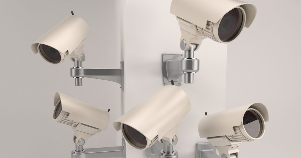 Multiple beige bullet-style CCTV cameras mounted on a wall, demonstrating common business surveillance cameras.